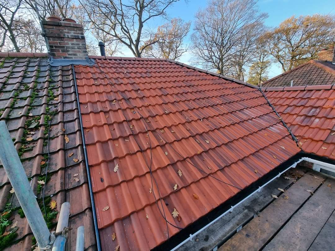 A repaired red tiled roof with a new lead valley and gutter