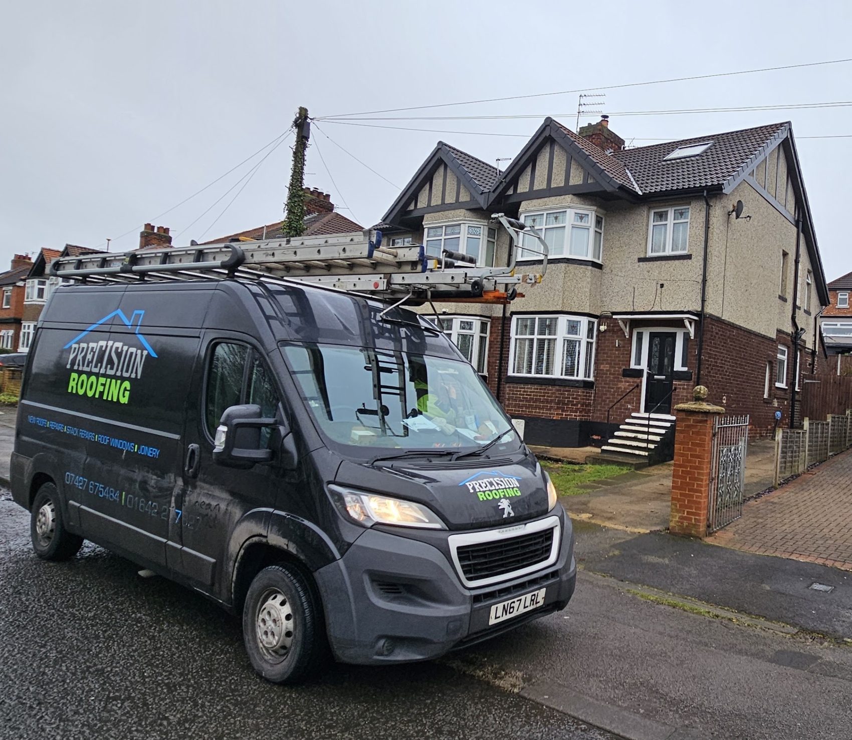 The black Precision Roofing van parked outside a bay-fronted semi with ladders on the roof