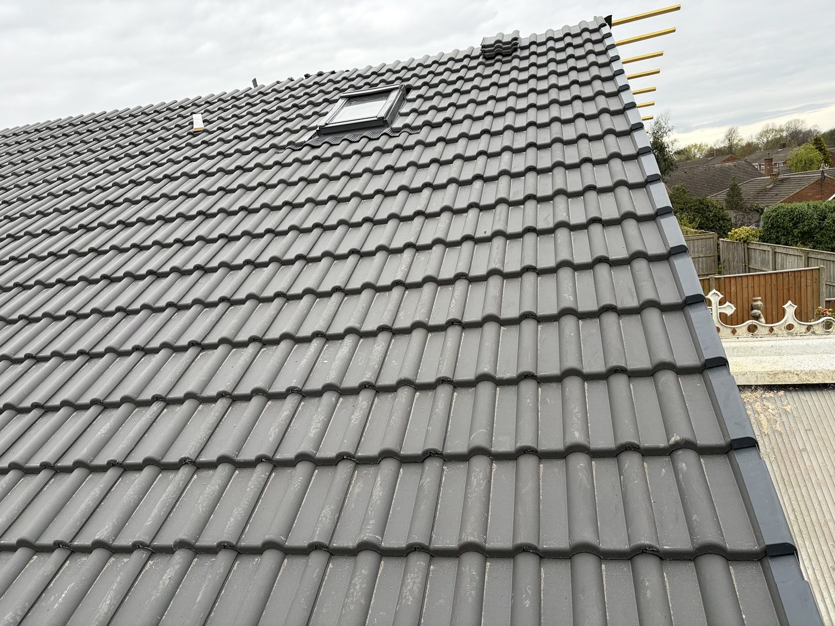 A finished grey tiled roof slope with a rooflight