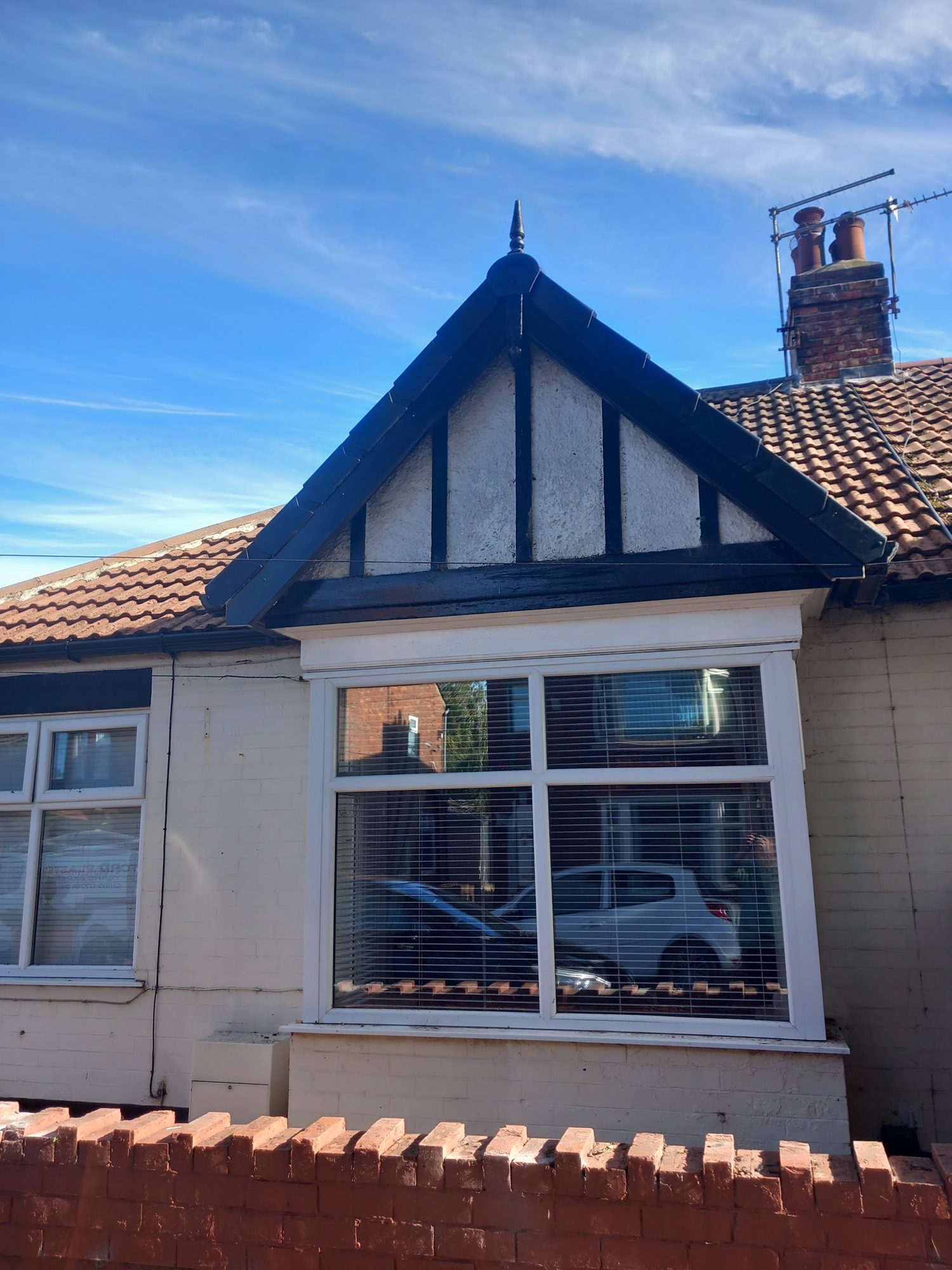 A gabled dormer with dark painted timbers over a bay window and a red tiled roof